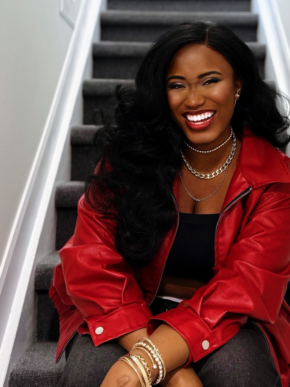 Ruova smiling on a staircase in a red jacket